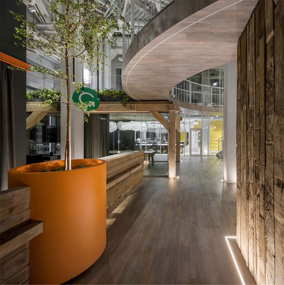 39 ý tưởng trang trí nội thất văn phòng đẹp > Ý tưởng trang trí nội thất văn phòng với bàn lễ tân bằng gỗ, cạnh đó là chiếc chậu cây màu cam khổng lồ