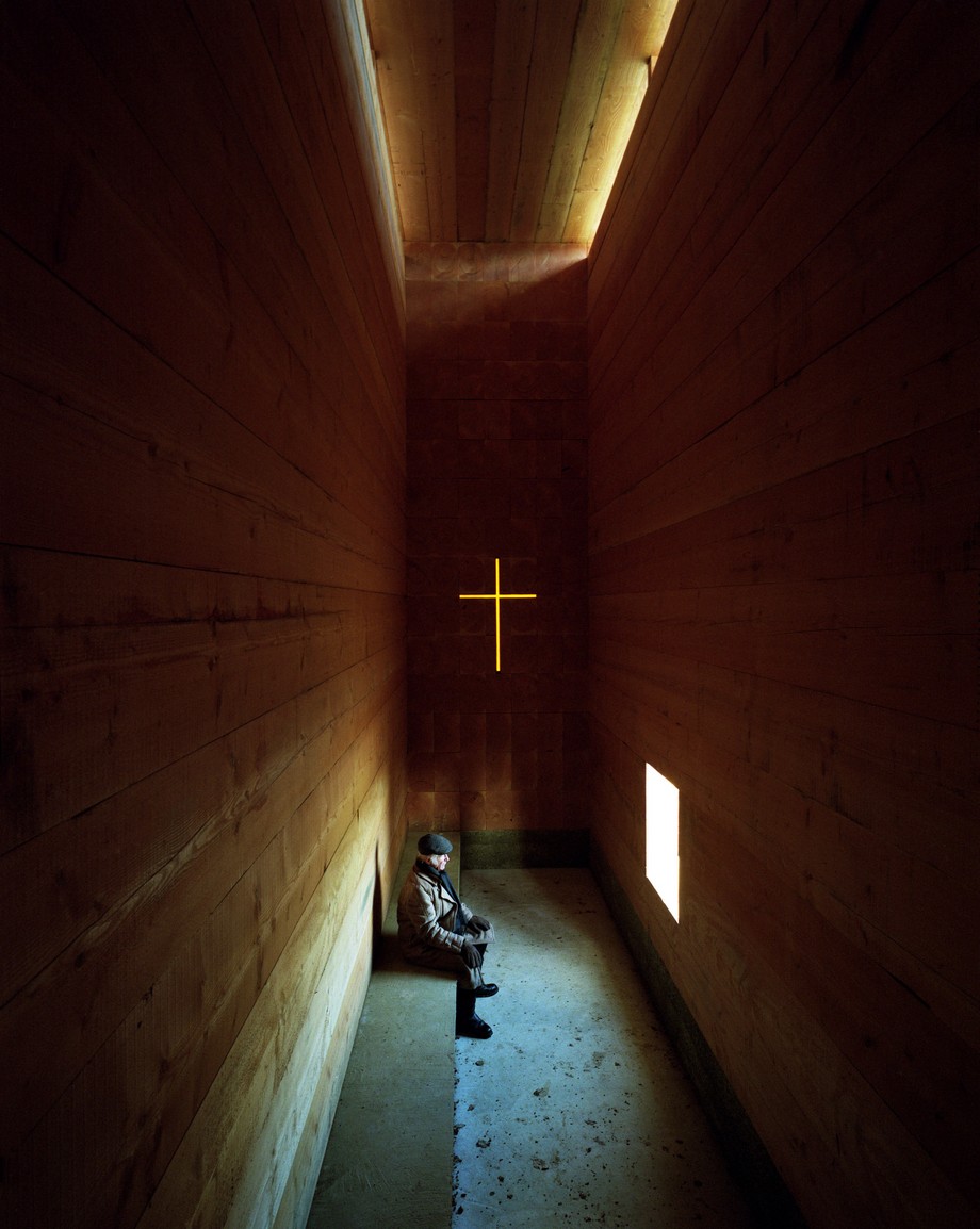 Khám phá mẫu thiết kế nhà thờ nhỏ bằng gỗ siêu ấn tượng từ những khối gỗ lớn > Thiết kế nhà thờ nhỏ bằng gỗ ấn tượng với một cây thánh giá được chạm khắc trên một bức tường và phát sáng